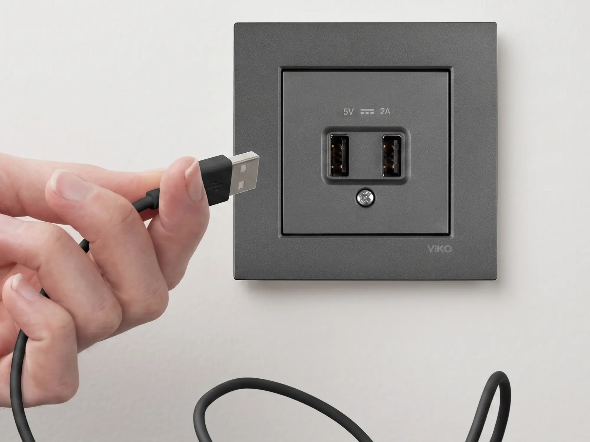 USB'li Priz Nedir, Nasıl Seçilir? Montaj ve Model Rehberi Beyaz duvar yüzeyinde USB-A ve USB-C girişli topraklı priz, telefon şarj kablosu bağlı halde yakın plan görünüyor | Levent Elektrik